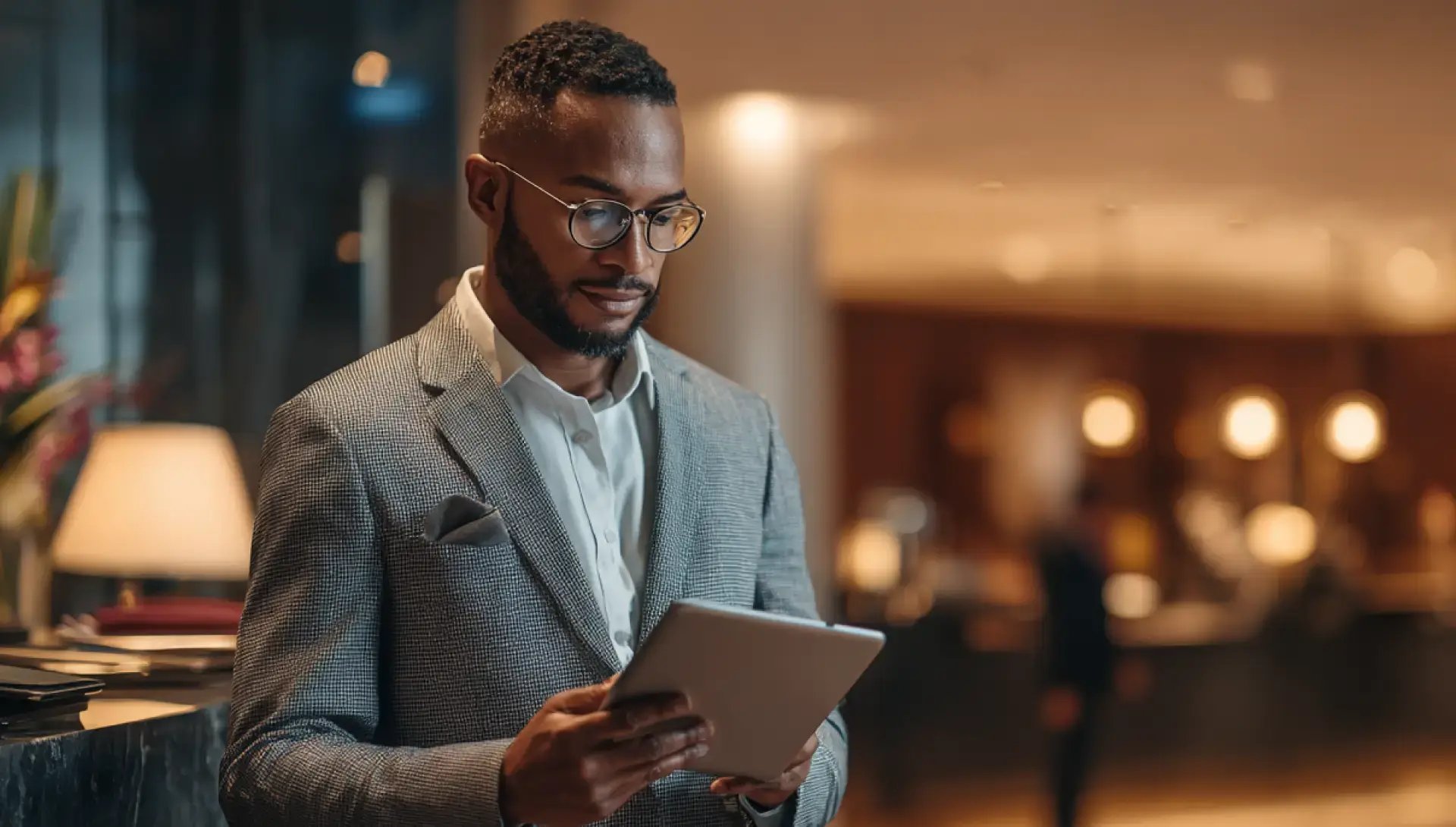Hotel manager in a modern lobby reviewing data on a tablet.