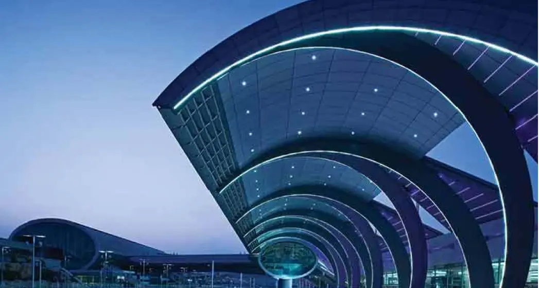 Futuristic airport architecture with curved roofs, illuminated lights, and a twilight sky, showcasing modern design.
